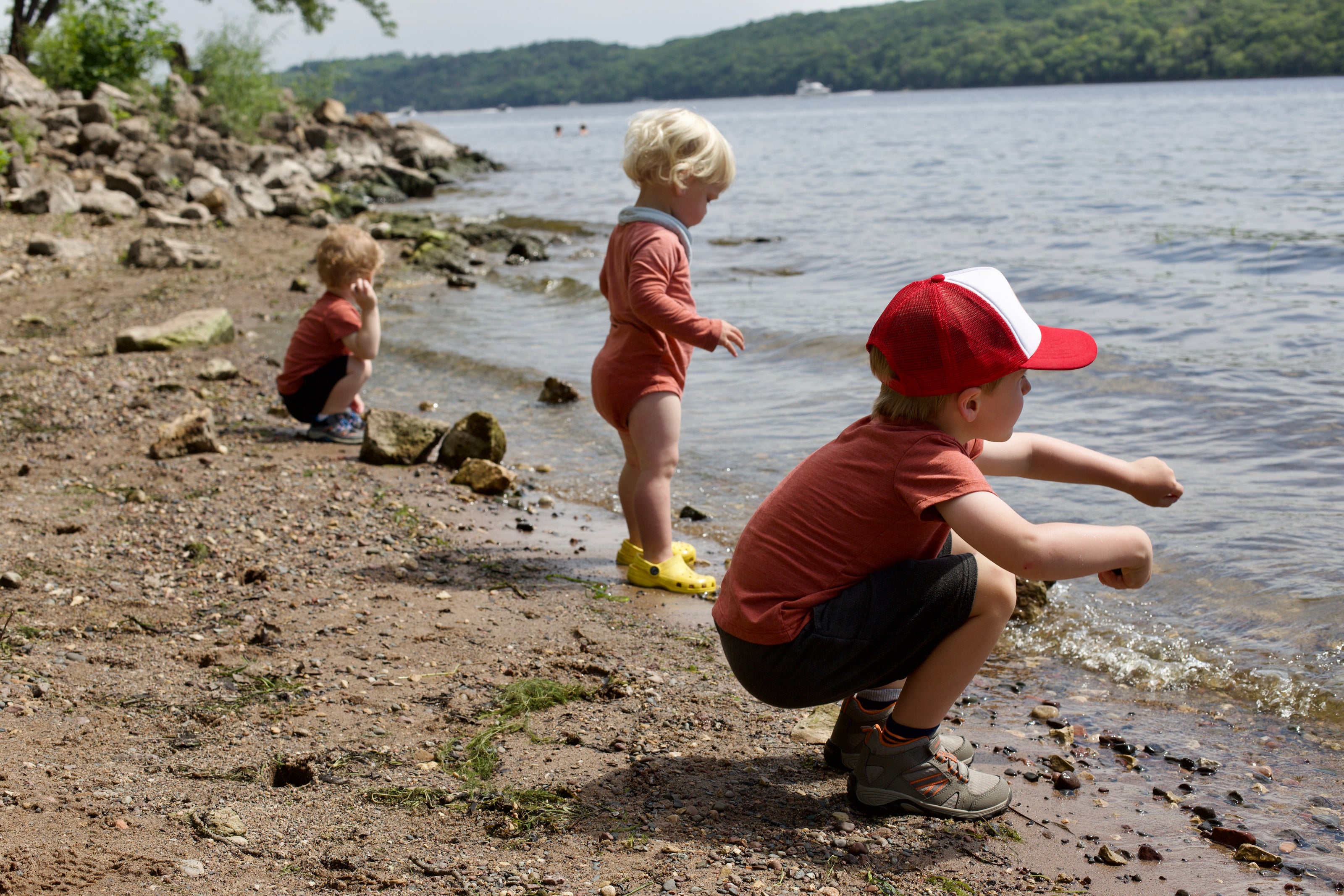 three toddlers skipping rocks at a lake